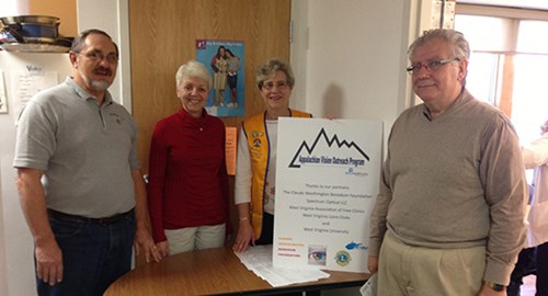 Group photo at a desk with Appalachian Vision Outreach Program screening clinic signage.