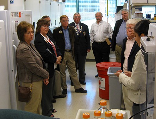 Lions members within a laboratory setting during a tour of the WVU Eye Institute Vision Research Center.