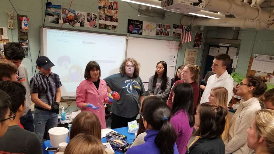teacher holding a brain model with a group of studnets