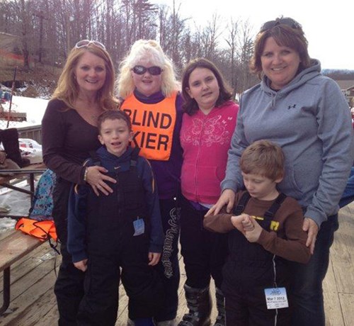 WV Lions Ski Program with members of WVU Eye Institute Children's Vision Outreach Program in an outside setting with snow on the ground.