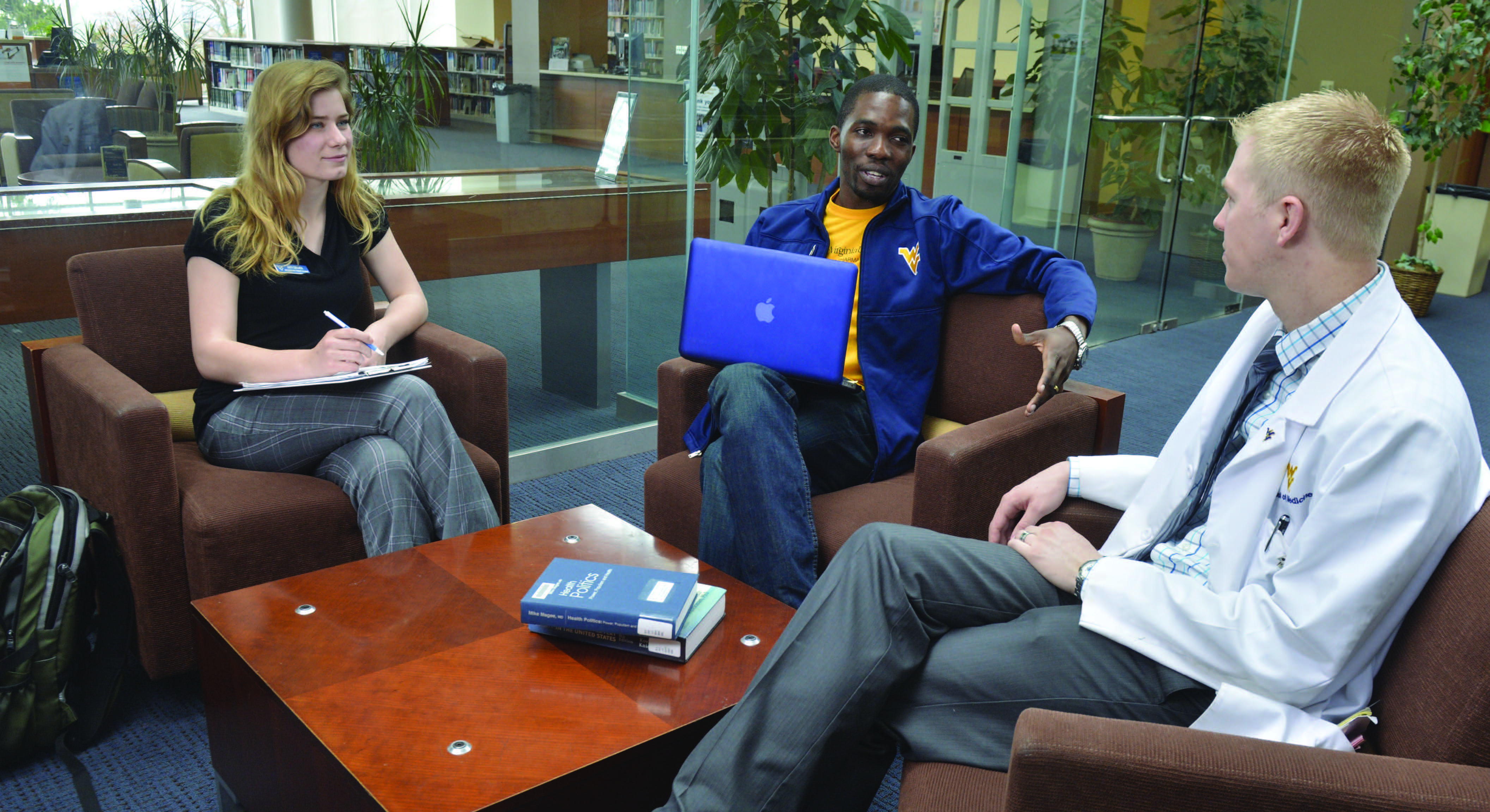 Three students sitting in chairs around a coffee table