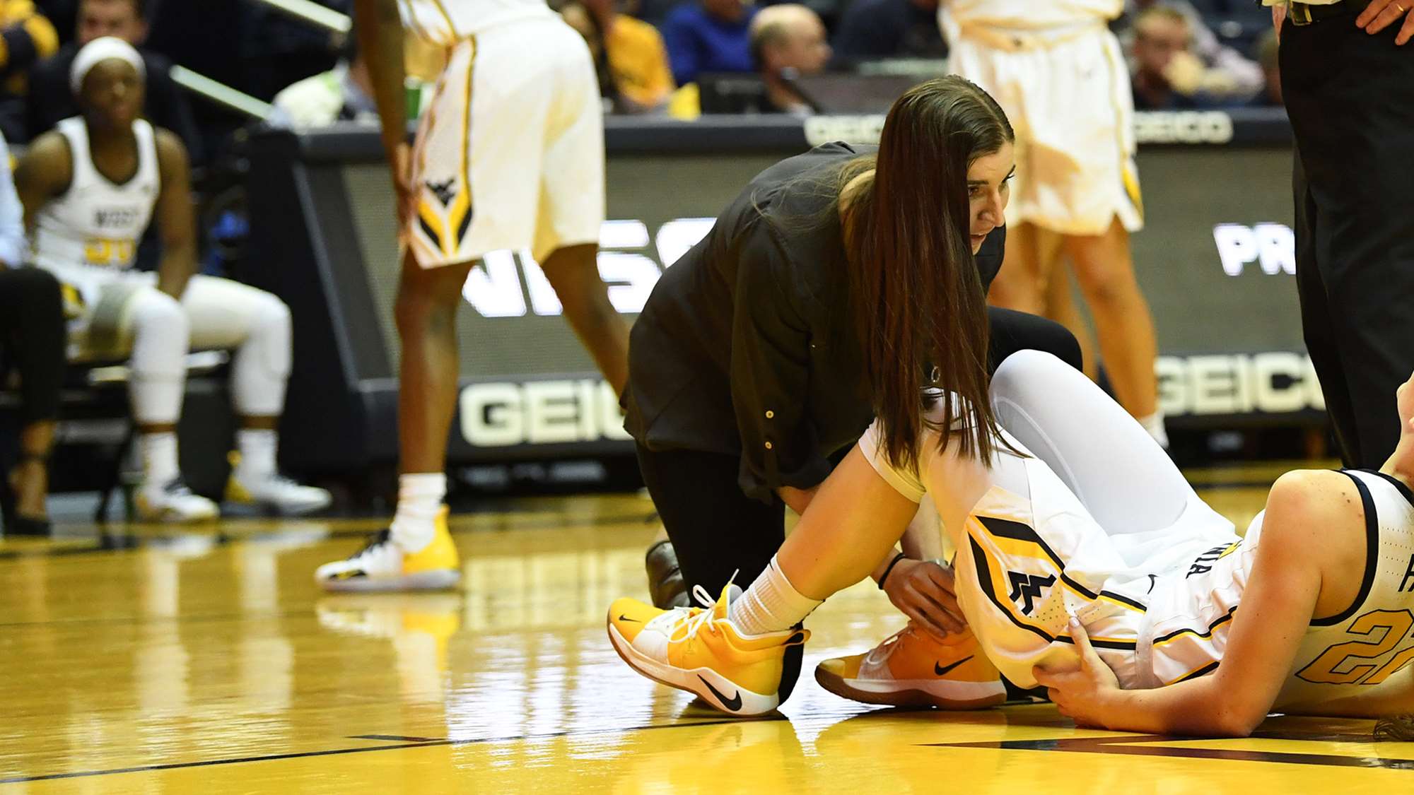 Athletic trainer tends to basketball player on court.