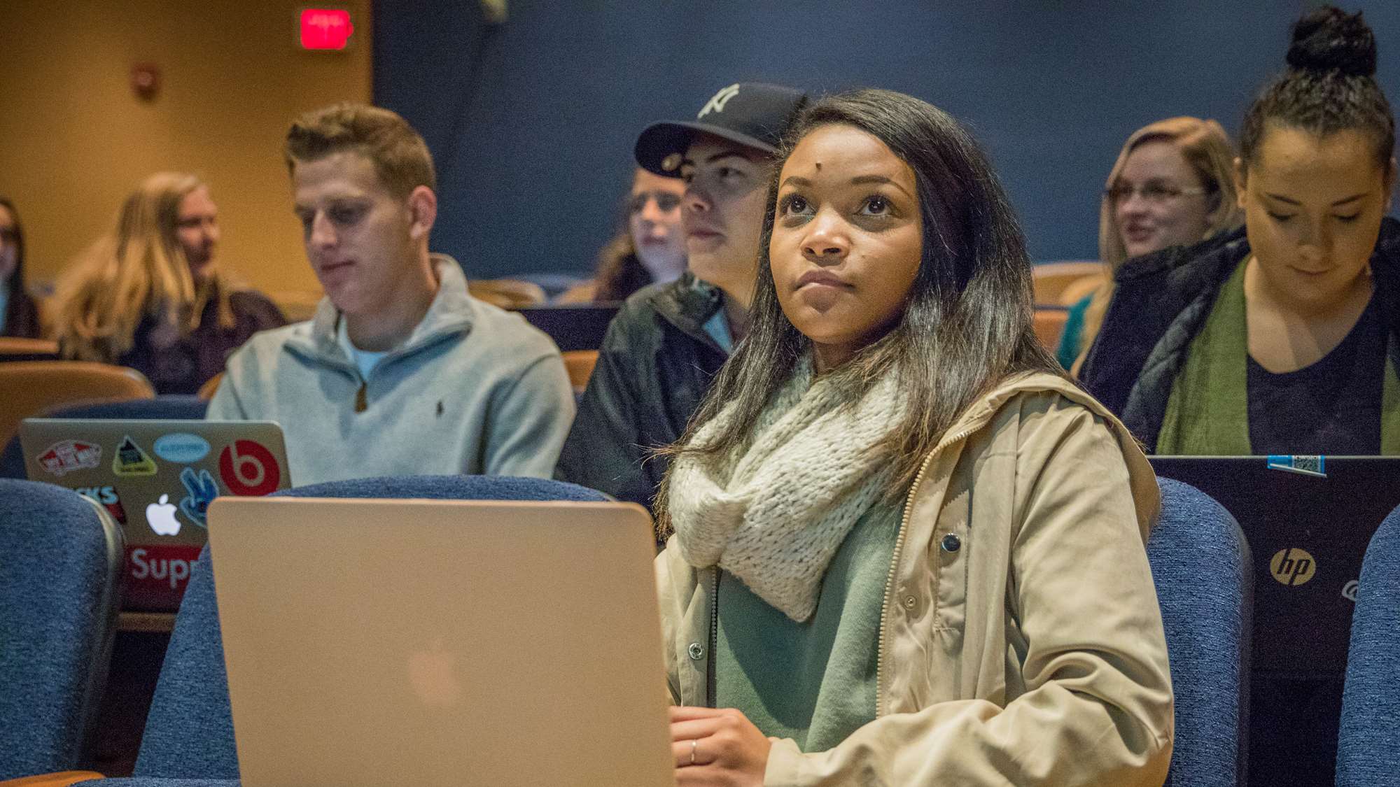 Female student in class with computer and other students in background