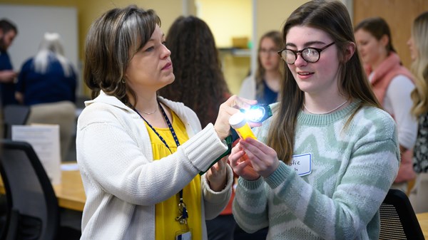 Faculty and student work together in an OT lab with others in background