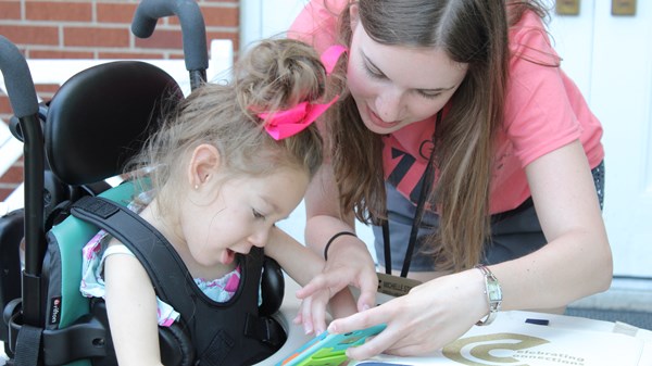 Female student helps female child patient with activity