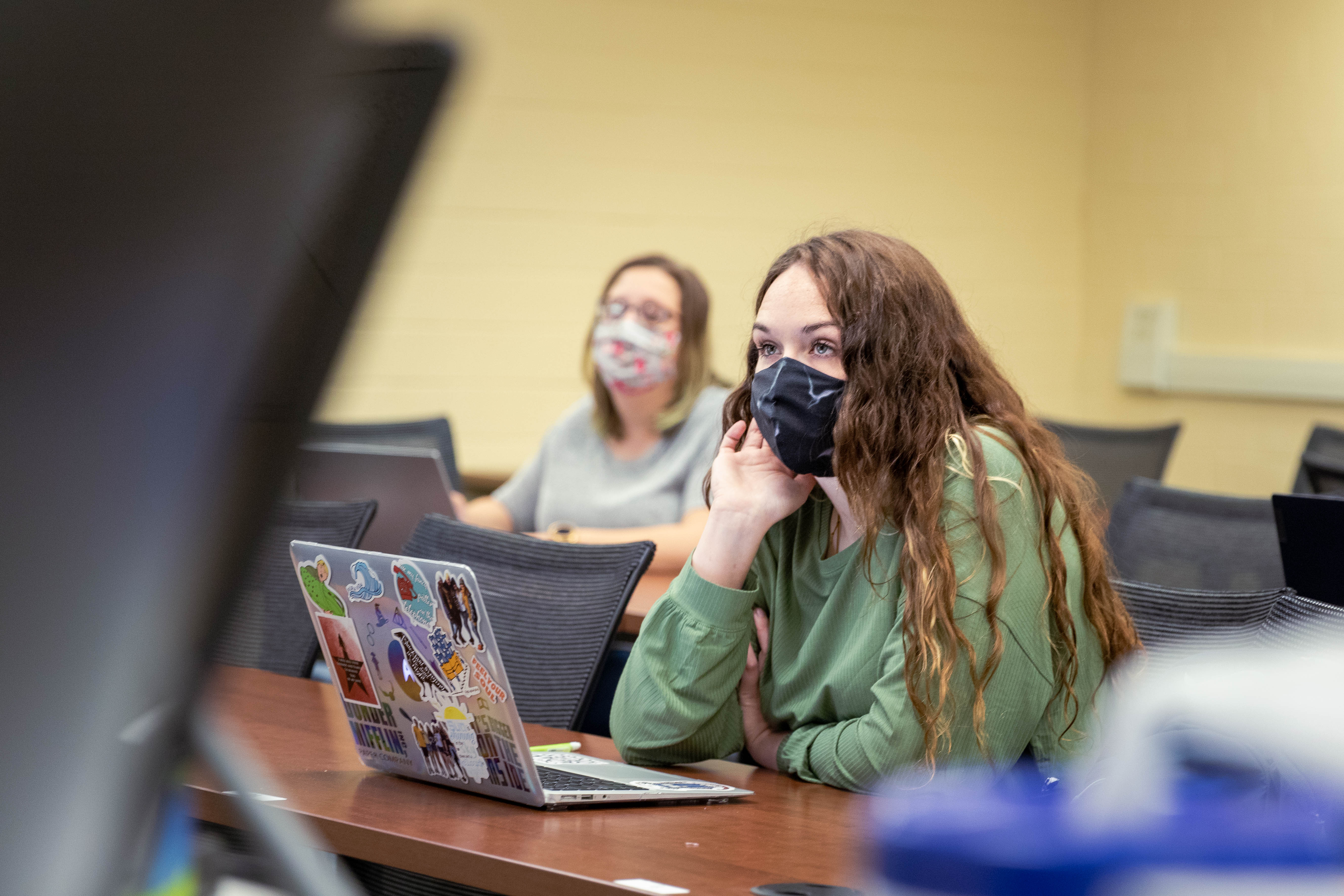 Students wearing masks and using laptops in classroom