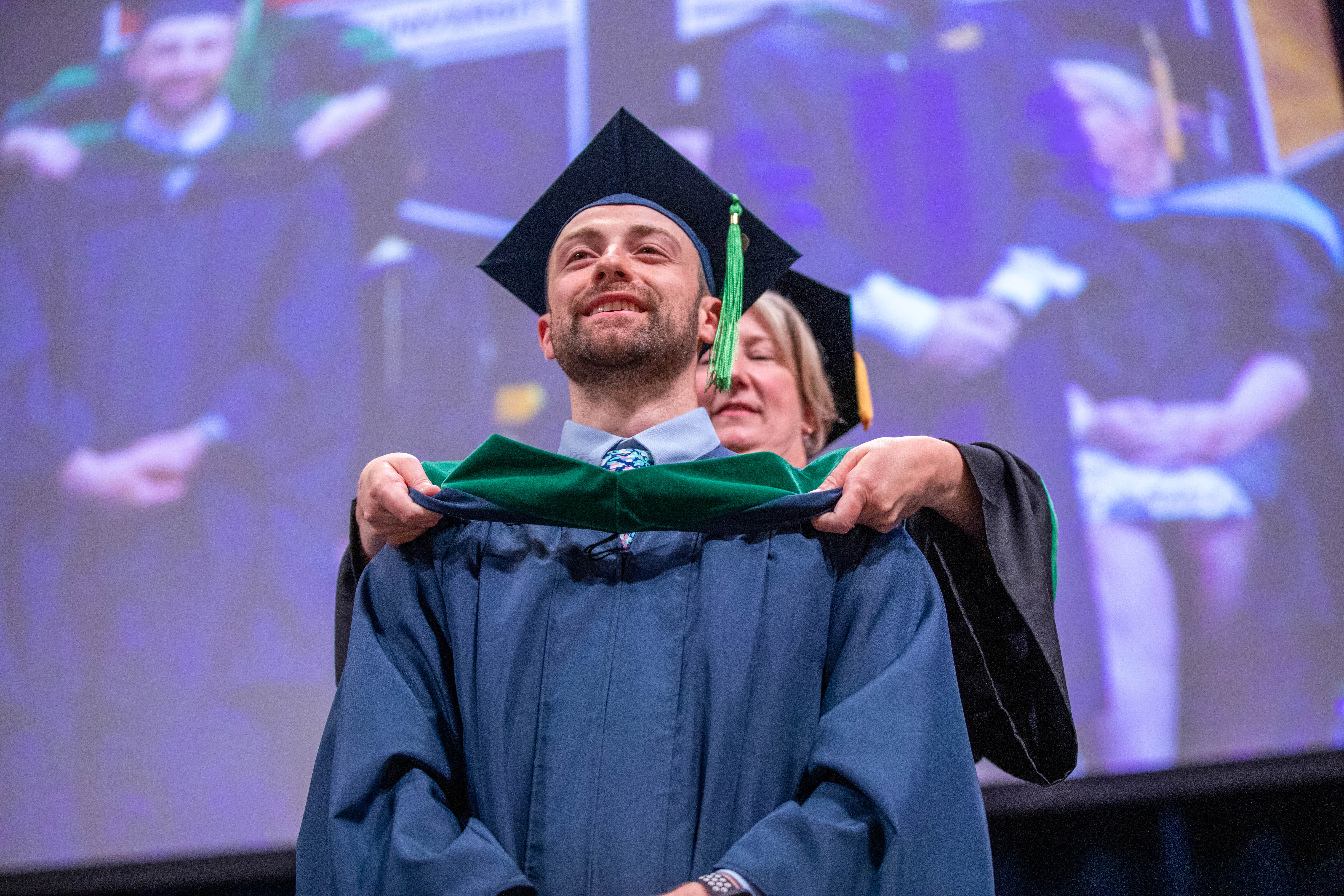 Student from first graduating Physician Assistant Studies class is hooded by Dr. Jennifer Momen during spring commencement 2022