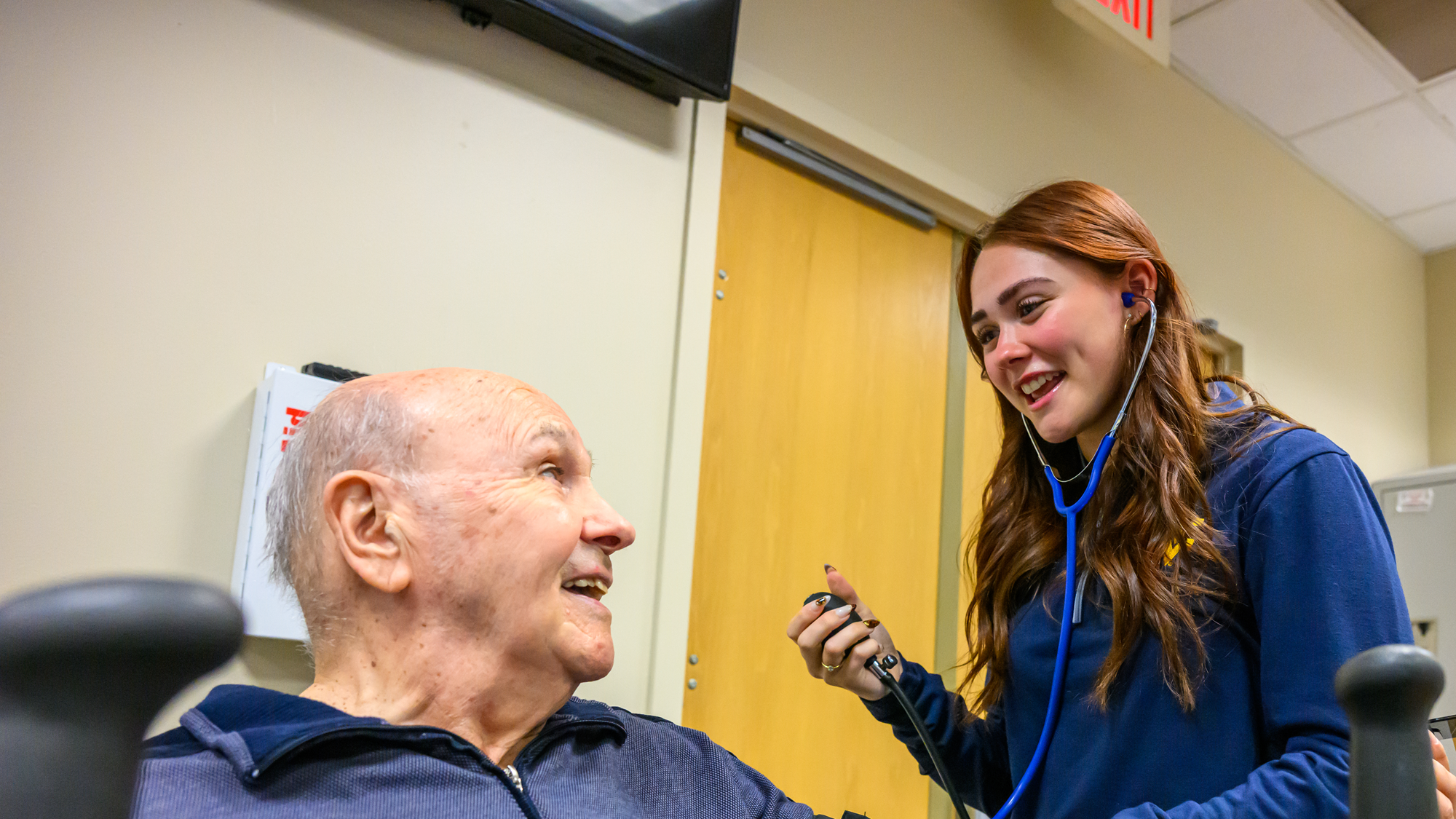 Female student manually takes older male patient's blood pressure