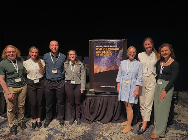 A group of preceptors standing buy a podium that reads WVU Pulmonary and Sleep Symposium.